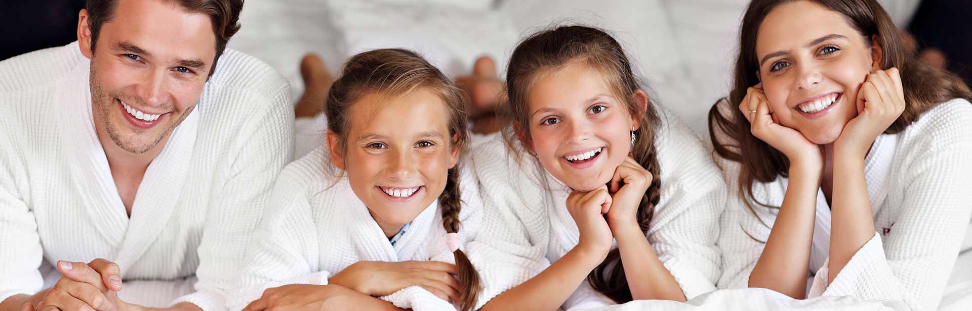 Familie im Bademantel auf dem Bett